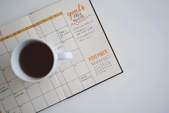 overhead view of calendar planner with coffee mug on top